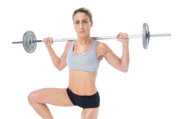 Strong female crossfitter lifting barbell behind head looking at camera