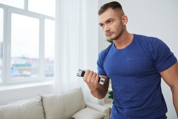 Man sportsman training at home with dumbbells, exercises for arms and back muscles, strong body and...