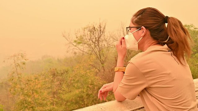 Worried Asian woman wearing n95 face mask for prevent bad air pollution. PM2.5 levels meaning the air quality posed a health hazard.