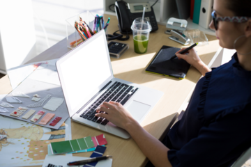 High angle view of female executive working over laptop and graphic tablet