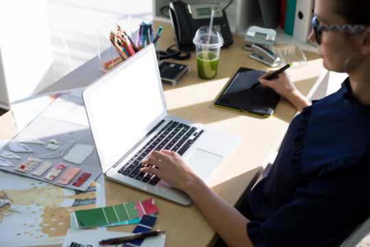 High angle view of female executive working over laptop and graphic tablet