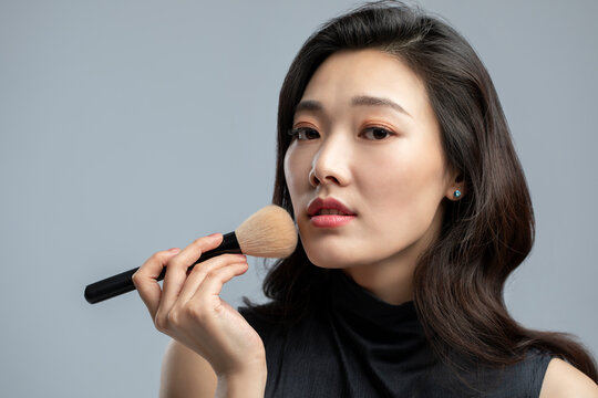 Young beautiful Chinese woman putting on make up