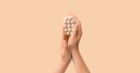 Female hands with massage soap bar on beige background