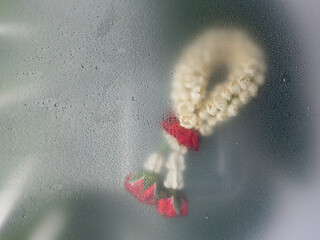 Beautiful Thai traditional style jasmine garland behind a white matte glass blurry with water...