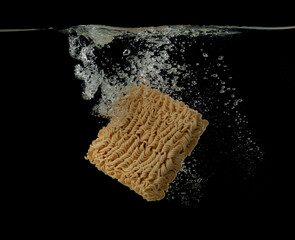 Instant noodles into water over dark background,cooking instant noodle