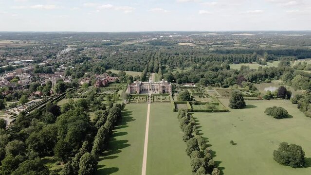 Hatfield House In Hertfordshire, UK - Jacobean Mansion With Picture-perfect Gardens And Protected Parkland On A Sunny Day. aerial pullback