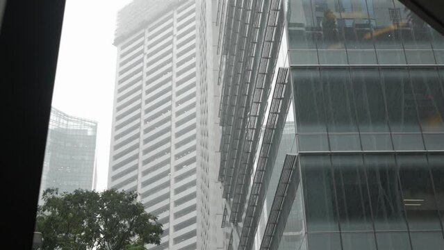 lower angle view up to the highrise skyscraper office financial building tower in the city of Singapore with stromy rain drop weather, tropical rain