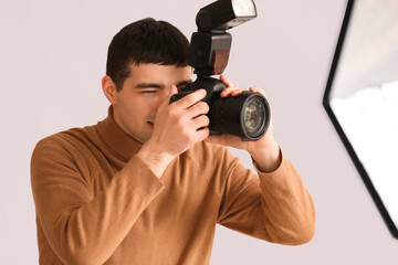 Fototapeta premium Young male photographer with professional camera in studio, closeup