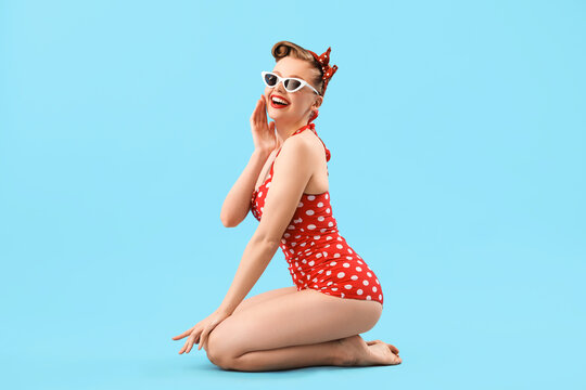 Young pin-up woman in polka dot swimsuit on blue background - Powered by Adobe
