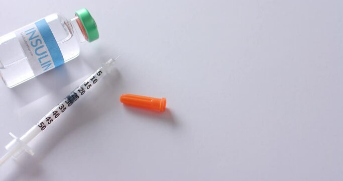 Close up of insulin vial and syringe on white background with copy space, slow motion