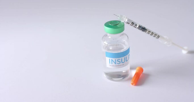 Close up of insulin vial and syringe on grey background with copy space, slow motion