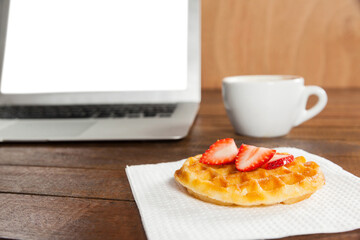 Laptop with strawberry waffle and coffee cup