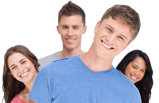 A man smiling with his head tilted and his friends behind him