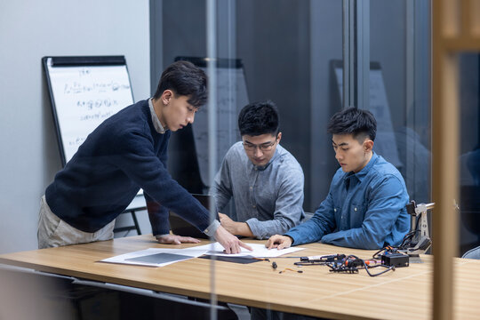 Confident Chinese designers checking a robotic arm