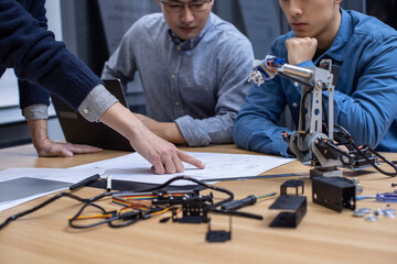Confident Chinese designers checking a robotic arm