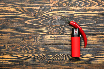 Spray with chili pepper on dark wooden background
