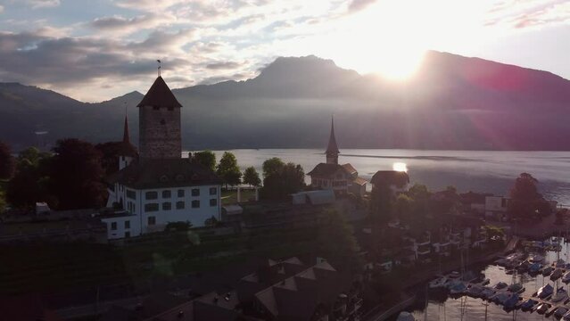 Fly over the schloss Spiez, castle in Switzerland during sunset. Fling towards lake and sun.canton bern