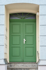 Fototapeta na wymiar View of old building with green wooden door and steps