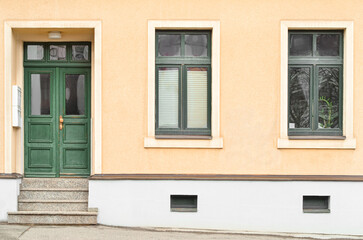 View of city building with green wooden door and windows