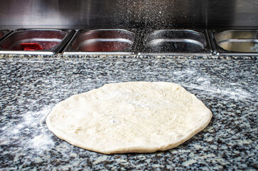 Pizza dough, on the table for cooking, flour
