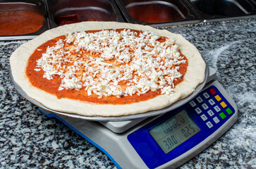 Cooking pizza, preparing dough with cheese on a kitchen scale