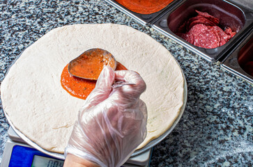 Cooking pizza by the chef, preparation of dough with sauce