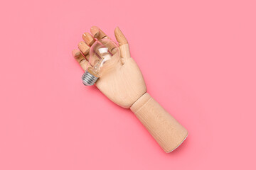 Wooden hand with light bulb on pink background. Insight concept