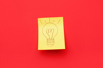 Sticky paper with drawn light bulb on red background. Insight concept