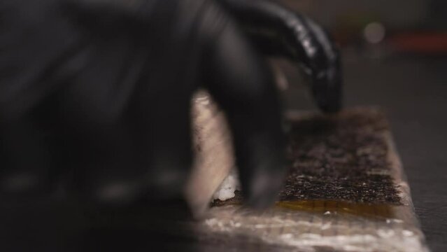 Process of making sushi. Master's hands making a sushi roll with bamboo mat.