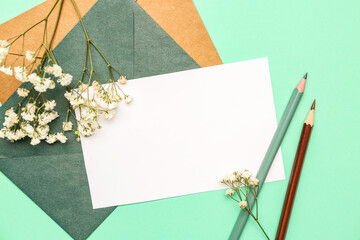 Composition with blank card, envelopes, pencils and gypsophila flowers on color background, closeup