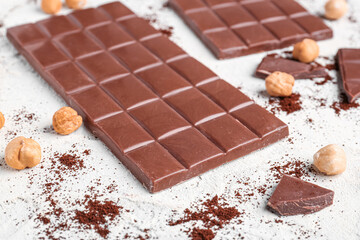 Tasty chocolate, hazelnuts and coffee powder on light background, closeup