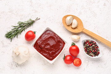 Composition with bowl of tasty tomato paste, garlic, peppercorn and rosemary on white grunge background