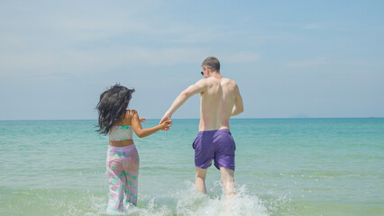 Couples hold hands and walk along the beach on their summer vacation and they smile and have fun on vacation.