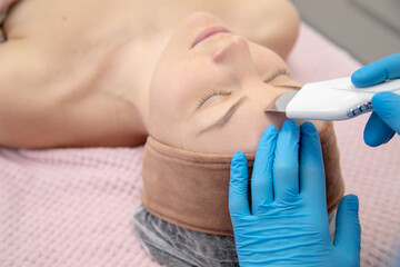 Dermatological doctor hands covered in gloves using Hydrafacial peel machine with spatula hand...