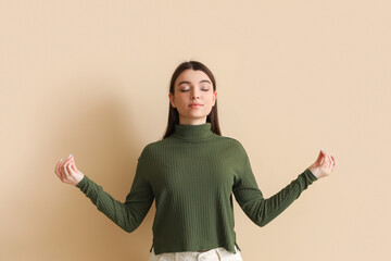 Meditating young woman on beige background