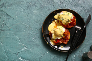Plate with tasty eggs Benedict on grey grunge table