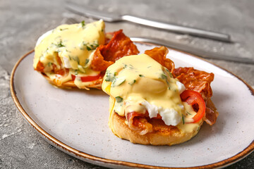 Plate with delicious eggs Benedict on grey grunge table