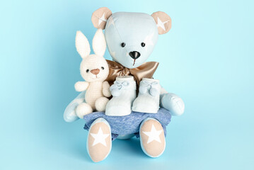 Toy bear and bunny with baby clothes on blue background