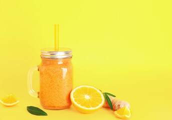 Mason jar of healthy orange smoothie with straw on yellow background