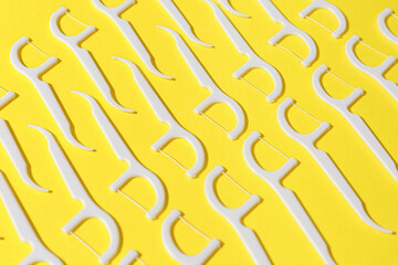 Many floss toothpicks on yellow background