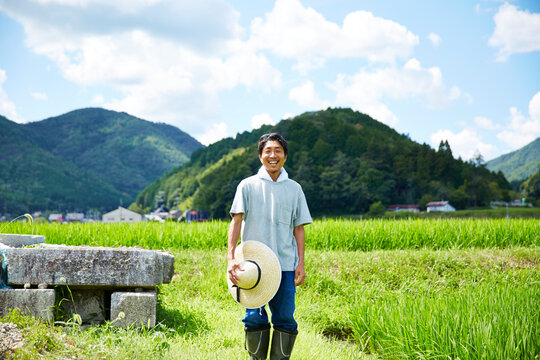 畦道に立つ笑顔の男性