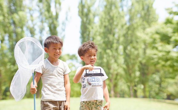 虫網とカブトムシが入った虫カゴを持つ兄弟