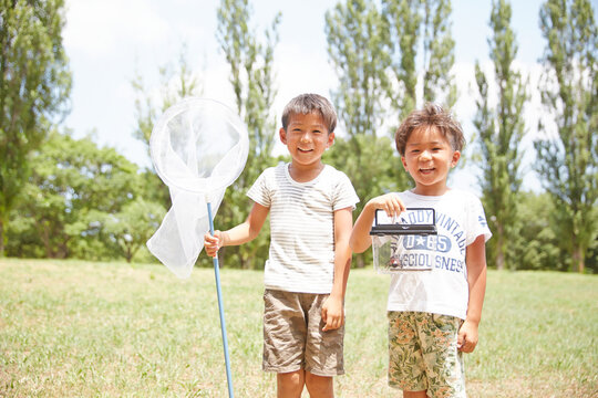 虫網とカブトムシが入った虫カゴを持つ兄弟