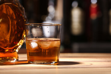 Bottle and glass of cold rum on table in bar