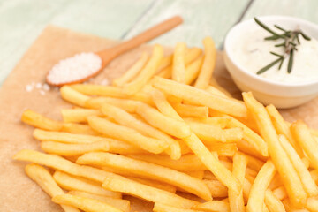 Tasty french fries, mayonnaise and salt on green wooden background