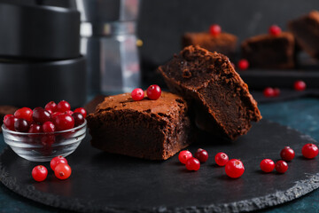 Board with pieces of tasty chocolate brownie on black background