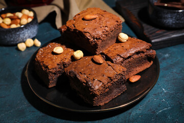 Plate with pieces of tasty chocolate brownie on black background