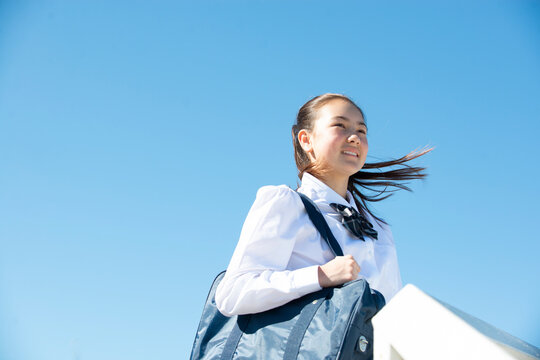 遠くを見て笑っている制服姿の女子学生