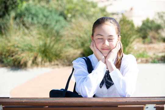 頬杖をついて目を閉じている制服姿の女子学生