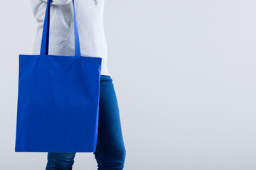Caucasian woman holding blue canvas bag with copy space on grey background